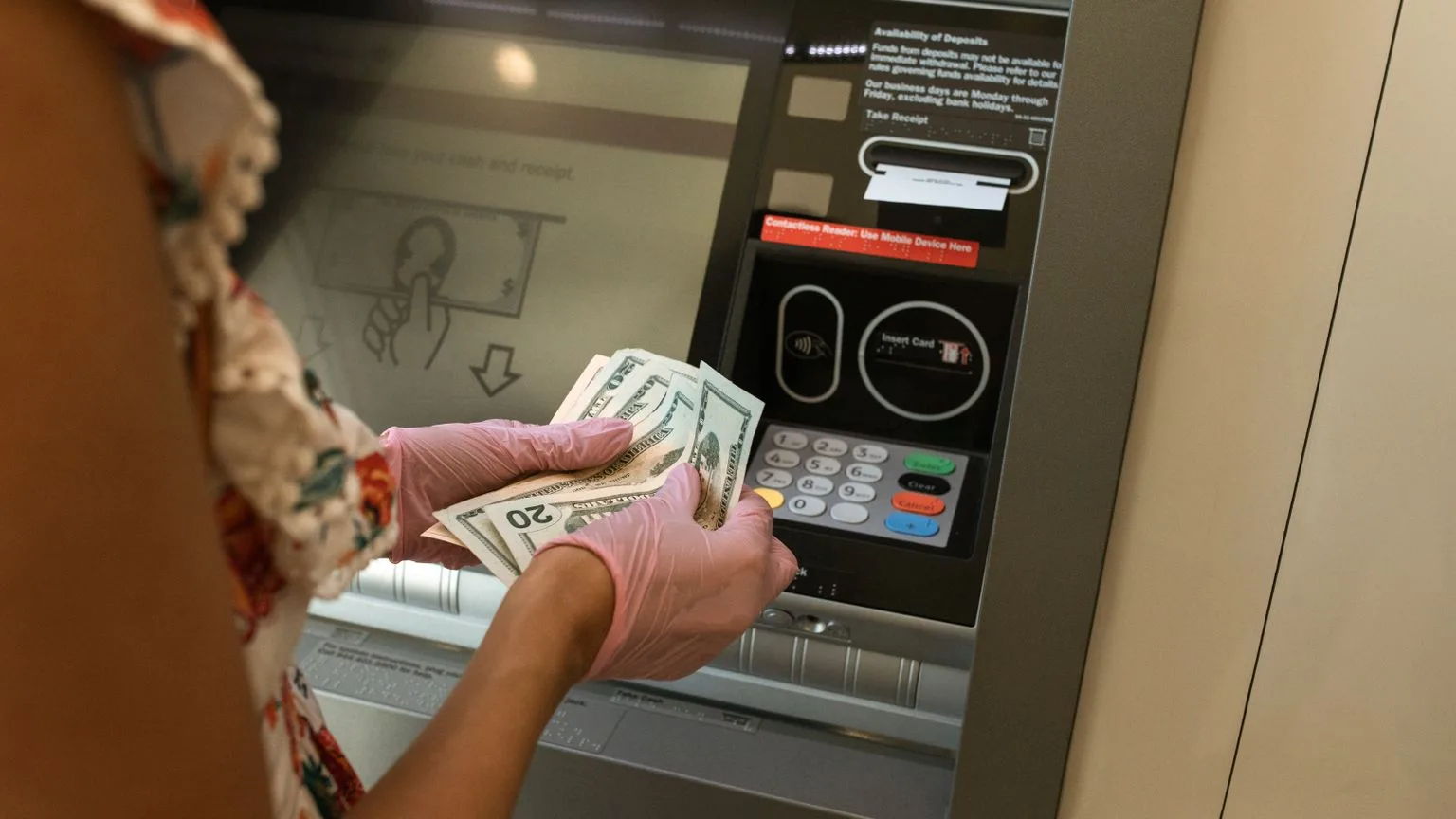 Hands taking twenty dollar bills from an ATM